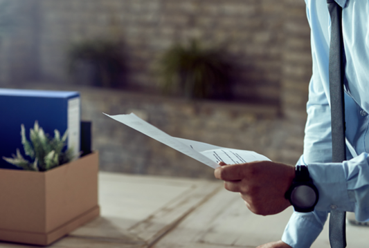 Person with a letter and packed box of office things