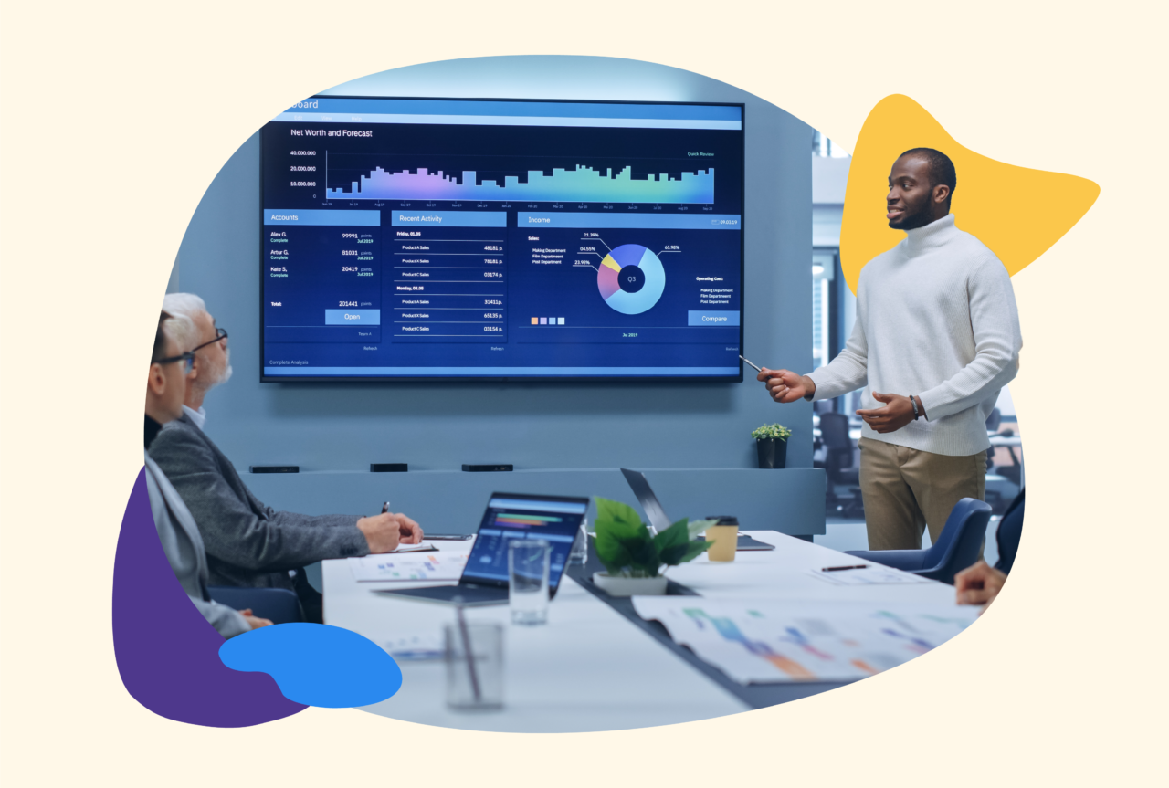 Three males in a meeting looking a data on screen together