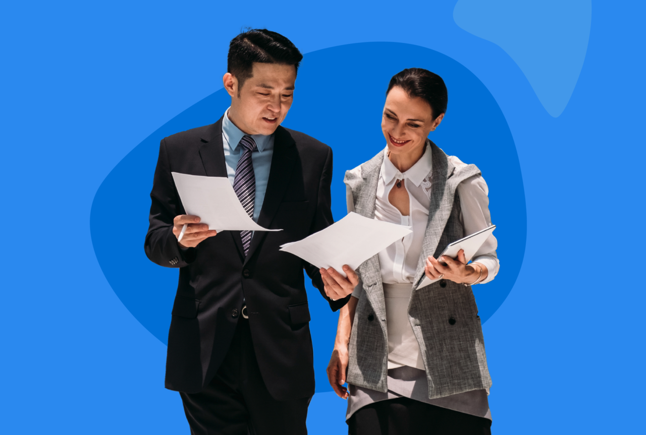 Two people smiling reading paperwork
