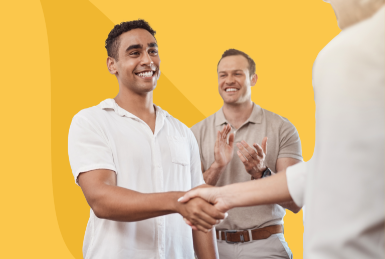 One man in the background clapping with another smiling man shaking someone's hand.