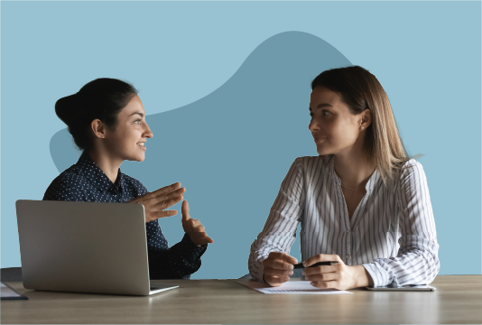 Two women sitting at a table talking.