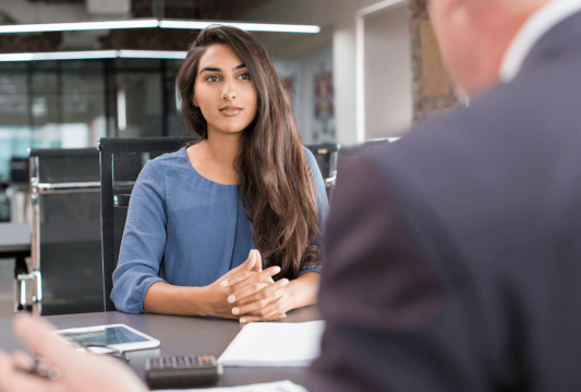 A woman sitting in a meeting with her hands crossed