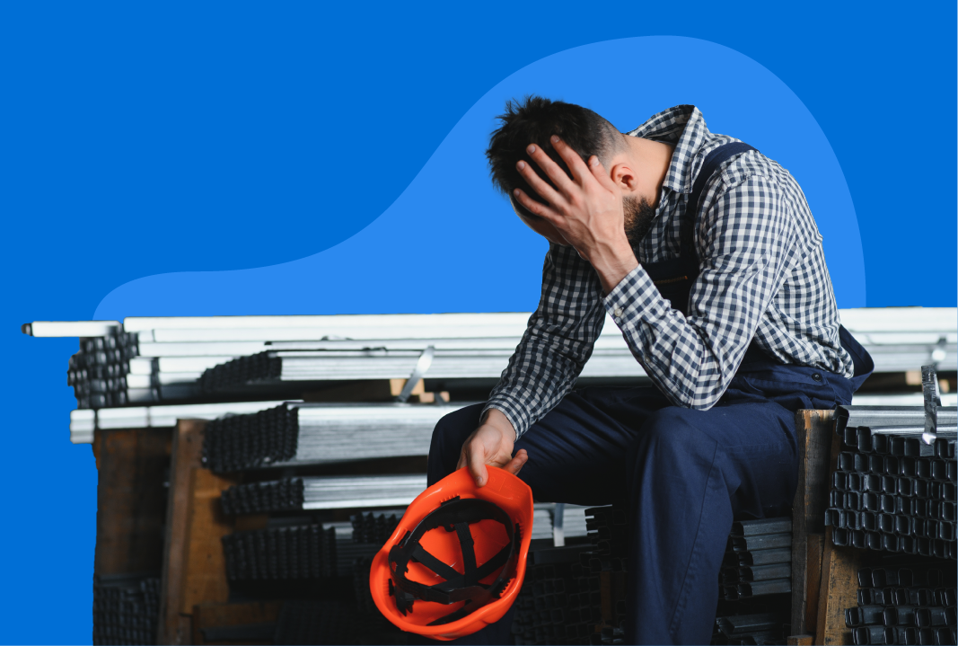 Construction employee sitting down and resting his head on his hand.