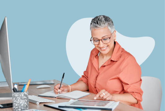 Employee with short grey hair and glasses filling out a survey at her work desk.