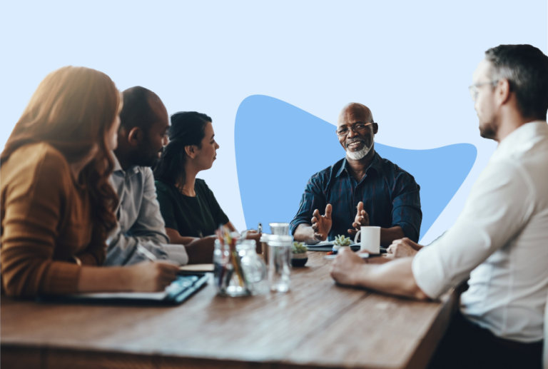 Five employees sitting around a conference table listening to the manager at the head of the table.
